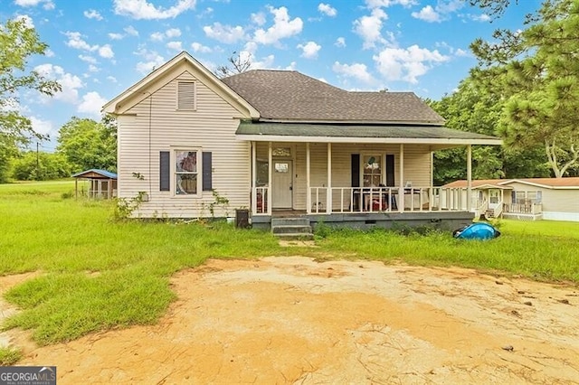 view of front facade featuring a porch, roof with shingles, and a front yard