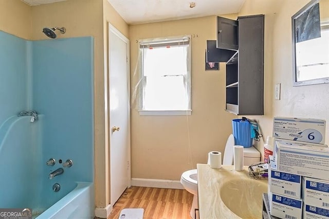 bathroom with bathtub / shower combination, wood-type flooring, and toilet