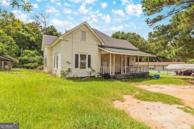 back of house featuring a porch, roof with shingles, and a lawn