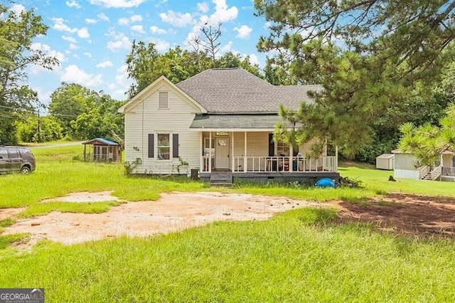 rear view of property featuring covered porch and a lawn