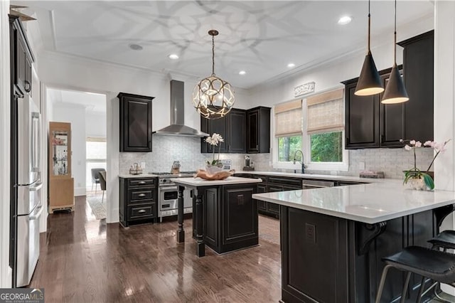 kitchen with wall chimney exhaust hood, a breakfast bar, decorative light fixtures, backsplash, and appliances with stainless steel finishes