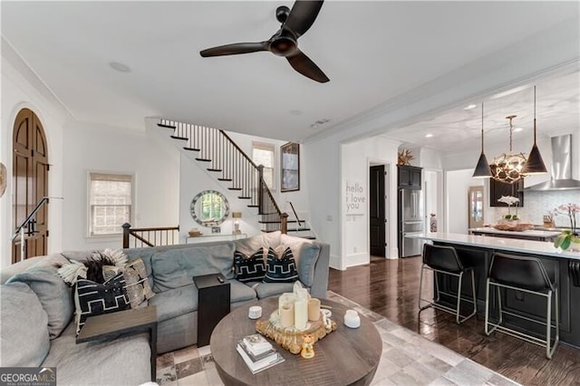 living room featuring ornamental molding, plenty of natural light, dark wood-type flooring, and ceiling fan with notable chandelier