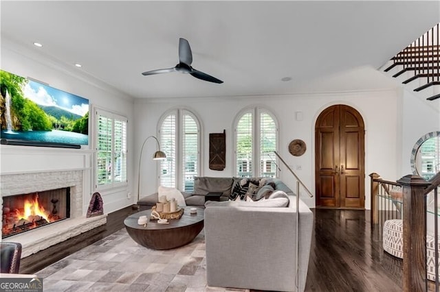 living room with a fireplace, crown molding, hardwood / wood-style floors, and ceiling fan