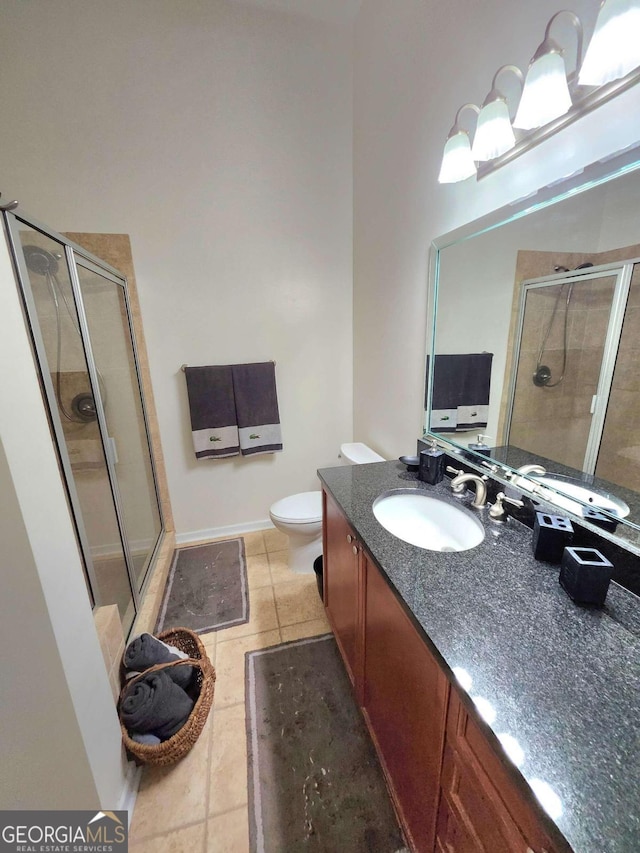 bathroom featuring vanity, a shower with door, toilet, and tile patterned flooring