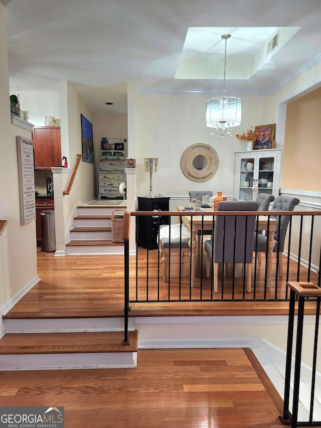 dining area featuring hardwood / wood-style flooring, a tray ceiling, and an inviting chandelier