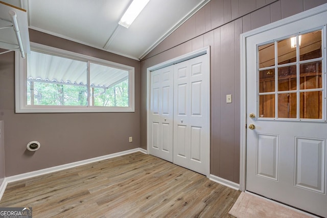 interior space with ornamental molding, light wood-type flooring, lofted ceiling, and wood walls