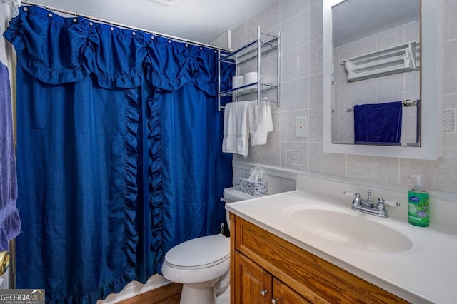 bathroom featuring tasteful backsplash, wood-type flooring, toilet, vanity, and tile walls