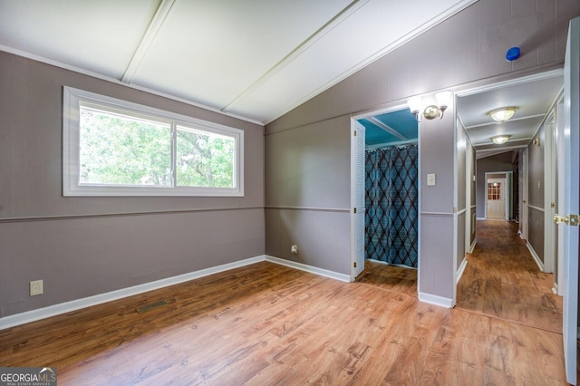 spare room with light hardwood / wood-style flooring and vaulted ceiling