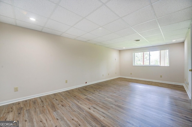 empty room with a drop ceiling and wood-type flooring