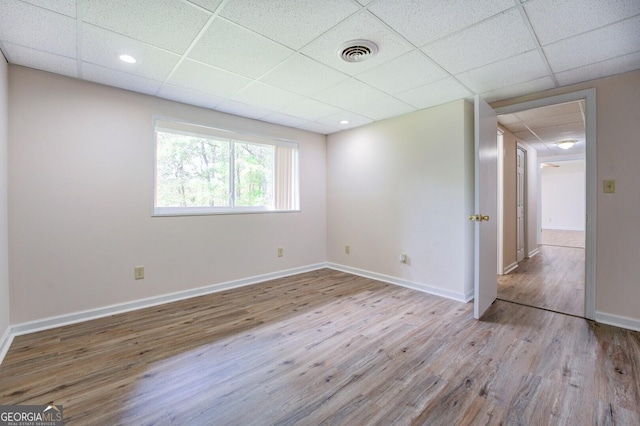 spare room featuring a paneled ceiling and light wood-type flooring