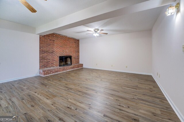 unfurnished living room featuring a fireplace, a textured ceiling, and hardwood / wood-style flooring