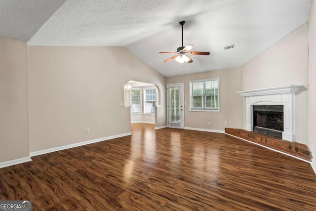 unfurnished living room with ceiling fan, dark wood-type flooring, a textured ceiling, and a brick fireplace