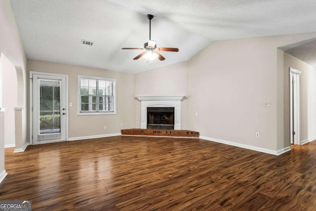 unfurnished living room featuring a textured ceiling, dark hardwood / wood-style flooring, ceiling fan, a fireplace, and vaulted ceiling