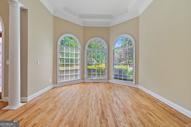 unfurnished room featuring decorative columns, light wood-type flooring, and a wealth of natural light