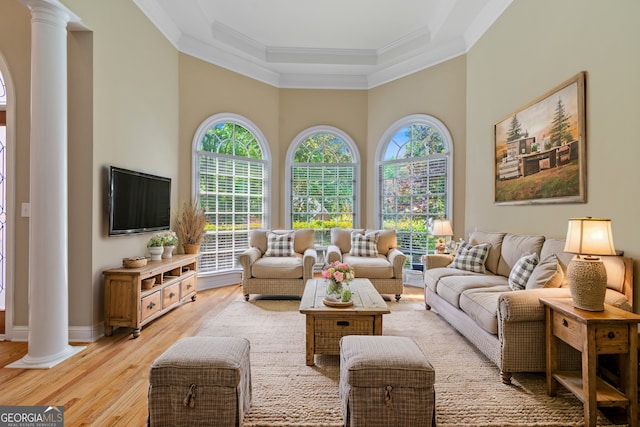 living room with crown molding, baseboards, decorative columns, and light wood finished floors