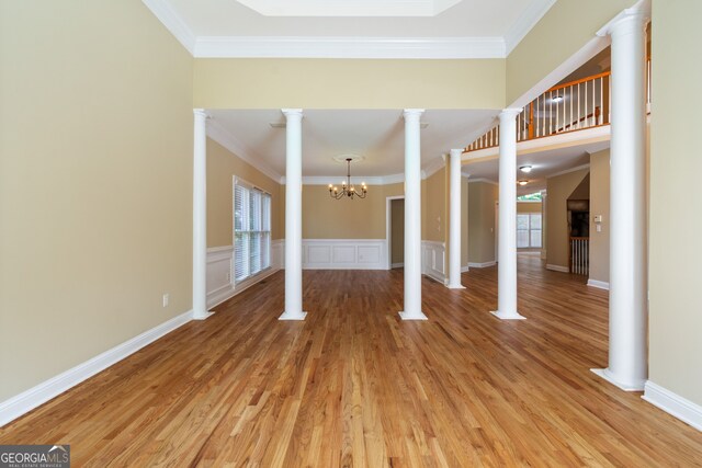 interior space featuring light hardwood / wood-style floors, a notable chandelier, crown molding, and decorative columns