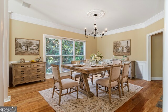 dining room featuring an inviting chandelier, crown molding, and light wood-type flooring