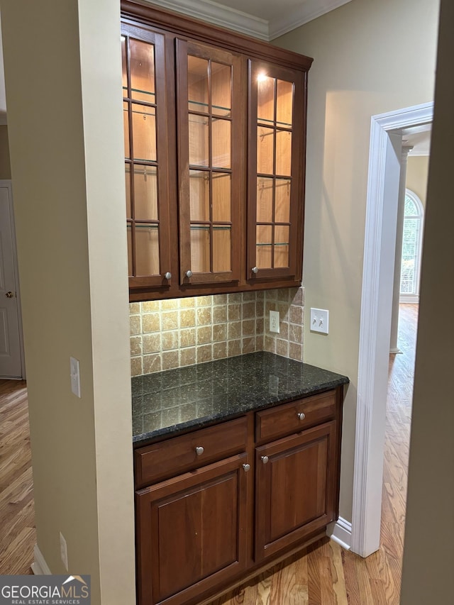 bar with baseboards, ornamental molding, light wood-style flooring, and decorative backsplash