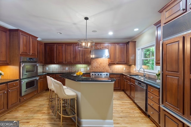 kitchen with a sink, exhaust hood, appliances with stainless steel finishes, a center island, and light wood finished floors