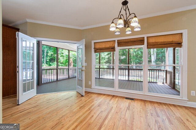 entryway featuring light hardwood / wood-style flooring, a healthy amount of sunlight, crown molding, and a chandelier