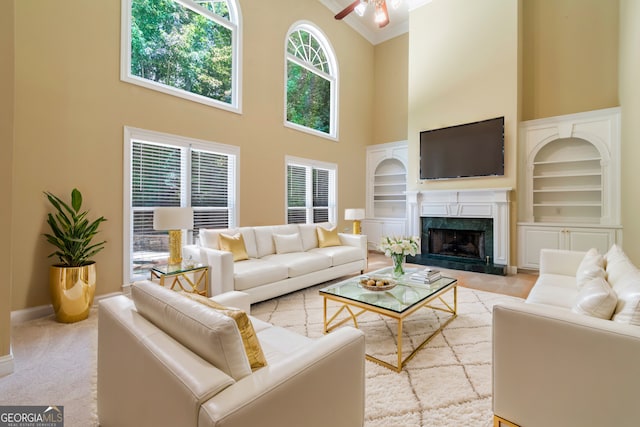 carpeted living room with baseboards, built in features, a premium fireplace, ornamental molding, and a high ceiling