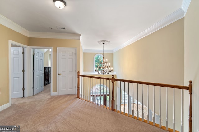 hallway with a chandelier, visible vents, baseboards, carpet, and crown molding