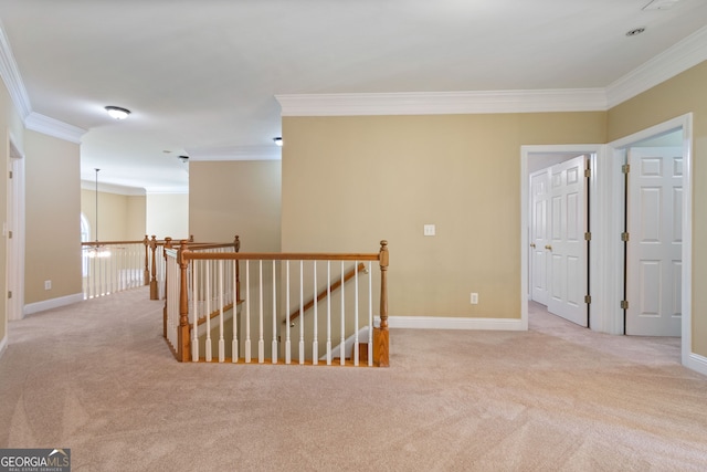 hall with ornamental molding, carpet, baseboards, and an upstairs landing