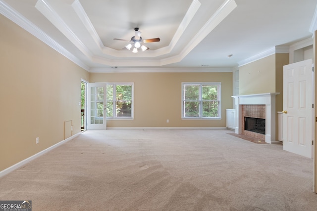 unfurnished living room featuring carpet floors, a fireplace, baseboards, ornamental molding, and a raised ceiling