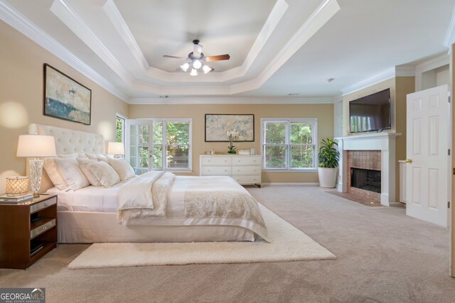 bedroom featuring light carpet, multiple windows, and a tray ceiling