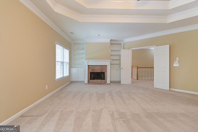 unfurnished living room with light colored carpet, baseboards, ornamental molding, a tray ceiling, and a tiled fireplace