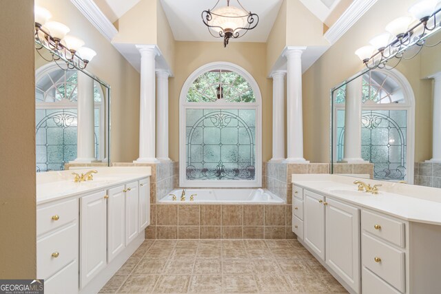 bathroom with tile patterned flooring, tiled tub, double vanity, and ornate columns