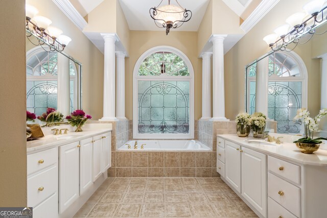 bathroom with a relaxing tiled tub, tile patterned flooring, decorative columns, and dual bowl vanity