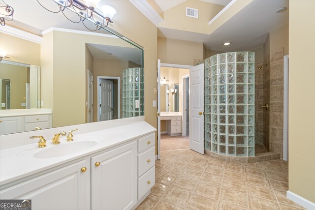 bathroom with vanity, a tile shower, tile patterned flooring, and crown molding