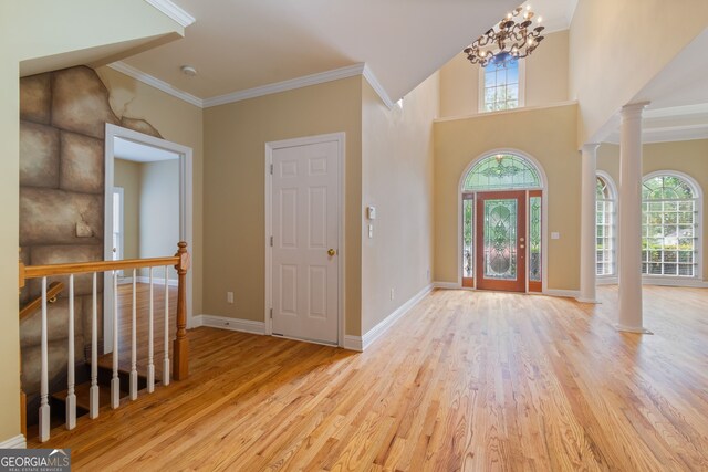 entryway featuring ornate columns, ornamental molding, a notable chandelier, and light hardwood / wood-style floors