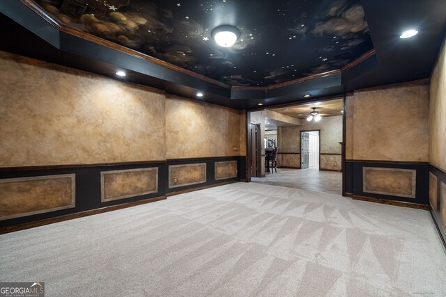 interior space featuring crown molding, light colored carpet, a raised ceiling, and ceiling fan