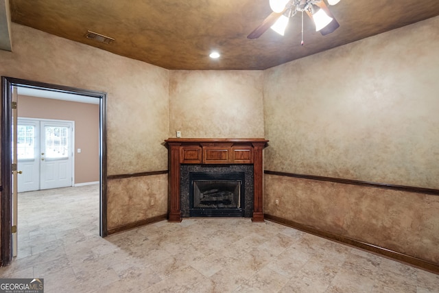 unfurnished living room with a ceiling fan, a fireplace, visible vents, and baseboards