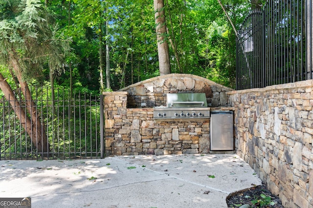 view of patio with area for grilling, an outdoor kitchen, and fence