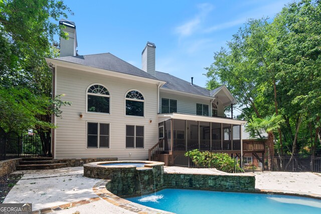 view of pool with a sunroom, an in ground hot tub, pool water feature, and a patio area