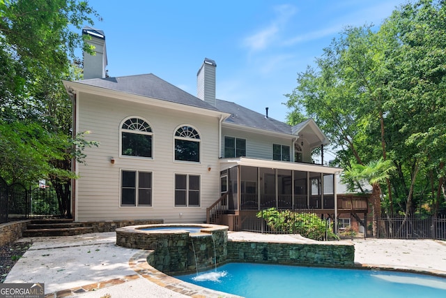 back of property featuring a patio, a chimney, a sunroom, fence, and an in ground hot tub