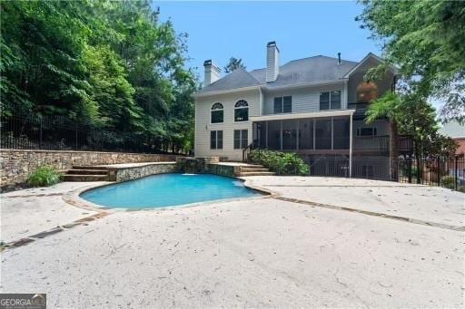 view of swimming pool featuring a sunroom, a patio area, and a fenced in pool