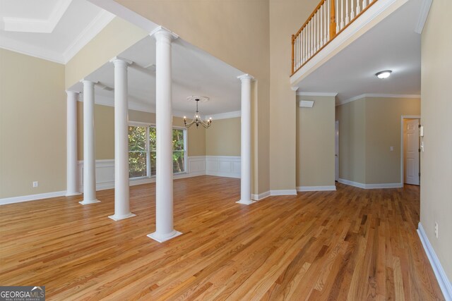 interior space featuring light hardwood / wood-style floors, ornamental molding, decorative columns, and an inviting chandelier