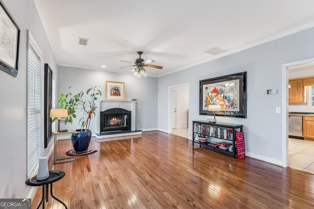 living room with wood-type flooring, ceiling fan, and crown molding