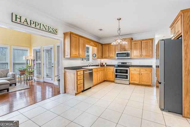 kitchen featuring appliances with stainless steel finishes, sink, light hardwood / wood-style floors, decorative light fixtures, and crown molding