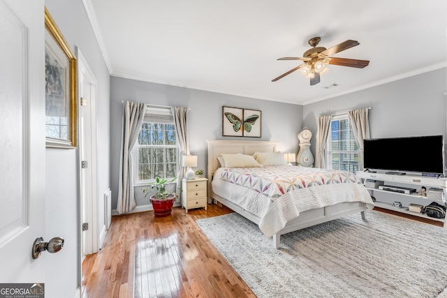 bedroom with light wood-style floors, baseboards, ornamental molding, and a ceiling fan