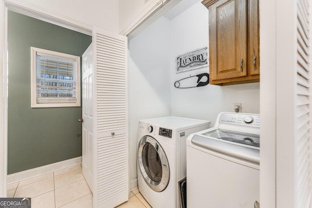 laundry area with light tile patterned floors, washer and clothes dryer, and cabinets