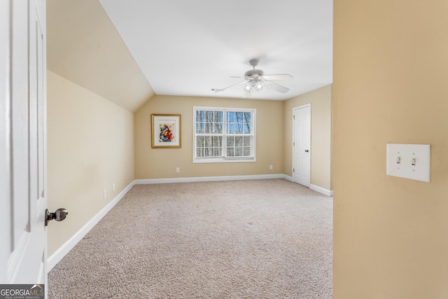 spare room with ceiling fan, vaulted ceiling, carpet flooring, and baseboards