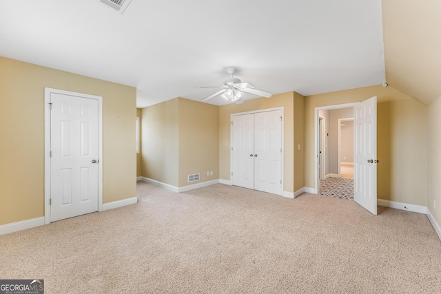 unfurnished bedroom with light carpet, vaulted ceiling, and ceiling fan