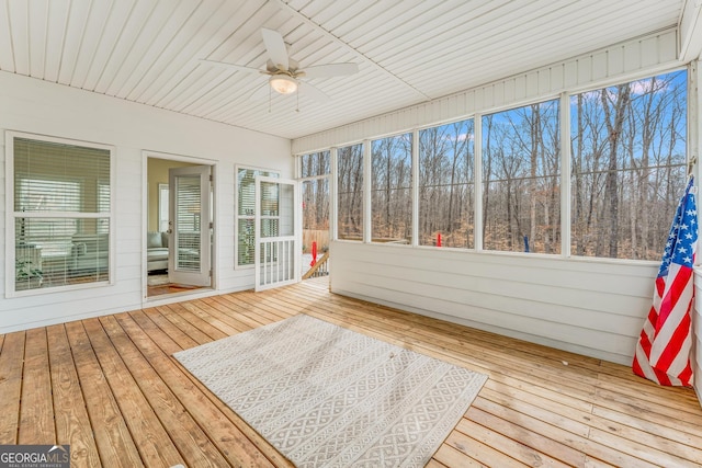 unfurnished sunroom featuring a healthy amount of sunlight, ceiling fan, and wood ceiling