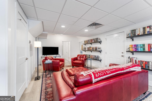 living room with light hardwood / wood-style flooring and a drop ceiling