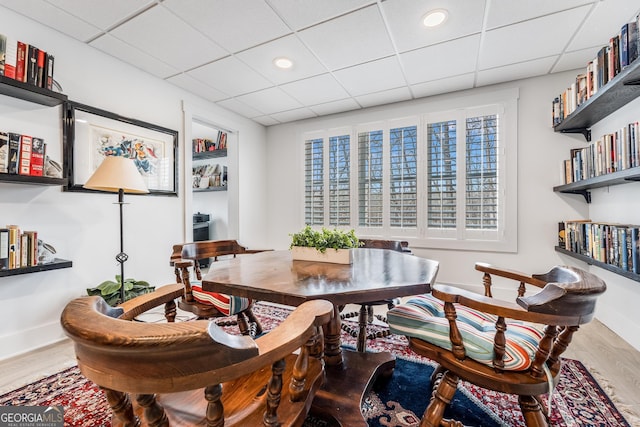 dining room with a paneled ceiling, baseboards, and wood finished floors